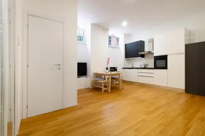a kitchen with white cabinets and a wooden floor at NOH Vatican Courtyard in Rome