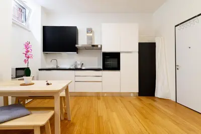 a kitchen with white cabinets and a wooden table at NOH Vatican Courtyard in Rome