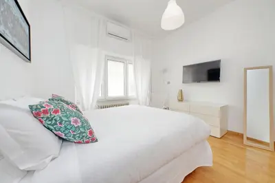 a white bedroom with a white bed and a television at YCH-Nice flat with patio near Vatican in Rome