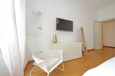 a bedroom with a white chair and a tv at YCH-Nice flat with patio near Vatican in Rome