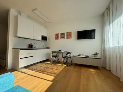 a kitchen with white cabinets and a table with chairs at GioLu Colosseo in Rome