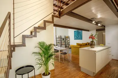 a kitchen and living room with a staircase in a loft at Liberti Colosseo - Luxury Apartment in Rome