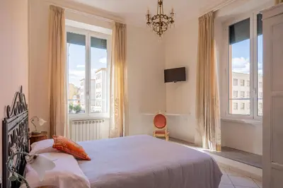 a bedroom with a large bed and two windows at Grandma Roma San Giovanni in Rome
