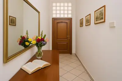 a hallway with a table with a vase of flowers and a book at Grandma Roma San Giovanni in Rome