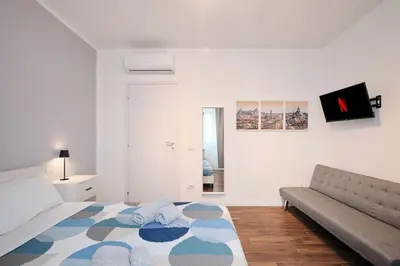 a white bedroom with a bed and a couch at Gens Iulia 2 Min da Stazione Trastevere by Hôtea in Rome