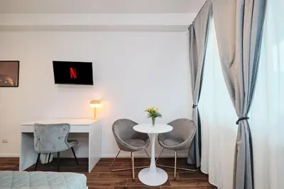 a room with a table and two chairs and a desk at Gens Iulia 2 Min da Stazione Trastevere by Hôtea in Rome