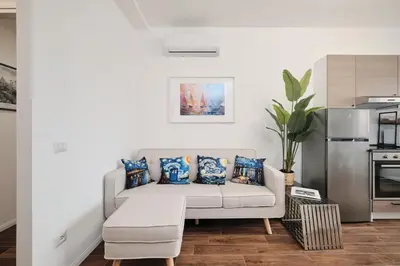 a living room with a couch and a kitchen at Gens Iulia 2 Min da Stazione Trastevere by Hôtea in Rome