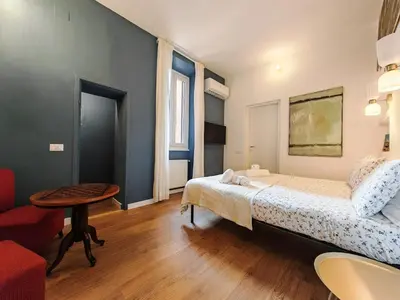 a bedroom with a bed and a table and a chair at Roman Forum Rooms in Rome
