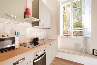 a kitchen with white cabinets and a window at Vatican Domus by BuddyRent in Rome