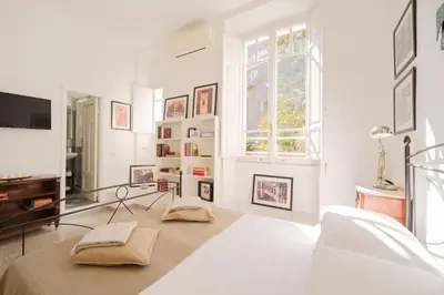 a white living room with a tv and a window at Vatican Domus by BuddyRent in Rome