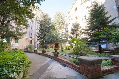 a brick path in a park with buildings and trees at Vatican Domus by BuddyRent in Rome
