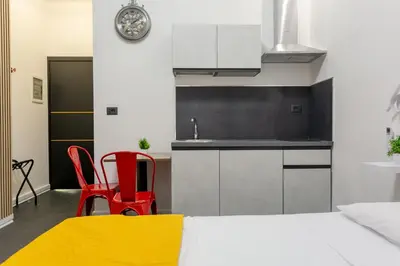 a kitchen with a bed and red chairs in a room at Le Regine - Home suites - Adult Only in Rome