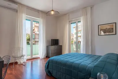 a bedroom with a blue bed and large windows at GuestHost - Close to St Peter in Rome