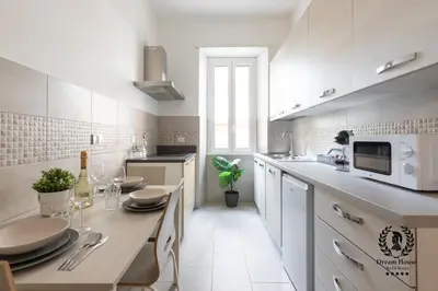 a white kitchen with a table and a microwave at Dream House Re di Roma - 50mt to Metro Station, central position, 4pax, 2bdr in Rome