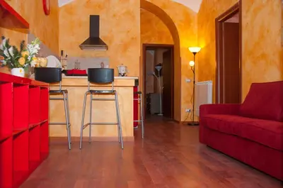 a living room with a red couch and a kitchen at Lucky Domus Esquilino in Rome
