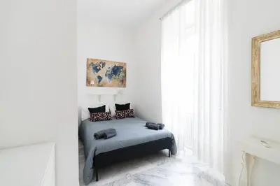 a bedroom with a bed in a white room at Hermès Apartment Rome in Rome