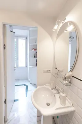 a white bathroom with a sink and a mirror at Hermès Apartment Rome in Rome