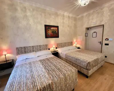 two beds in a hotel room with two lamps at Venus Inn Vatican Guest House in Rome