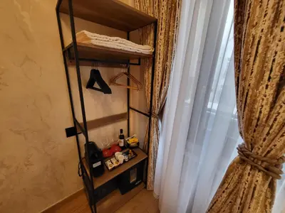 a room with a shelf and a window with curtains at Venus Inn Vatican Guest House in Rome