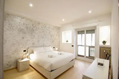 a bedroom with a white bed and a stone wall at HC - Baldo degli Ubaldi Elegant Apartment in Rome
