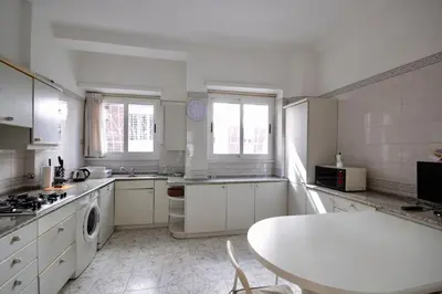 a kitchen with white cabinets and a table in it at HC - Baldo degli Ubaldi Elegant Apartment in Rome