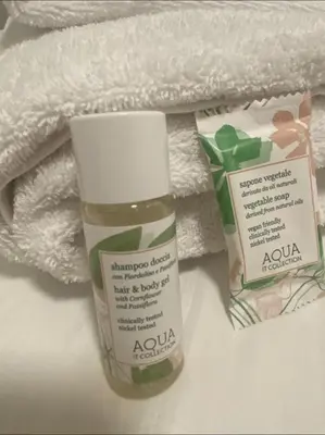 a pile of towels and a bottle of ayula products at Cozy Colosseo in Rome