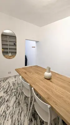 a wooden table with white chairs and a mirror at Abbituè Apartment in Rome