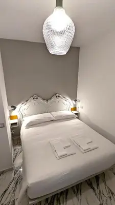 a white bedroom with a large bed with a chandelier at Abbituè Apartment in Rome