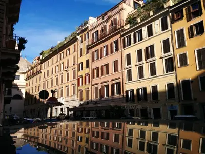 a reflection of buildings in a puddle in a street at Abbituè Apartment in Rome