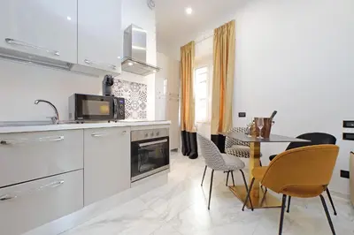 a kitchen with white cabinets and a table and chairs at Duplex Elegante a 2 Min dal Vaticano e dalla Metro in Rome