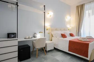 a bedroom with a bed and a table and a chair at Magnoliahome Suites at the Vatican in Rome