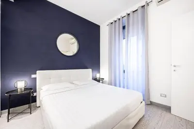 a bedroom with a white bed and a mirror at Casa Sistina in Rome
