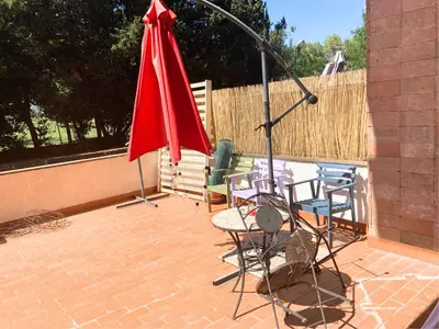 a patio with a table and chairs and a red umbrella at Terracito! in Rome