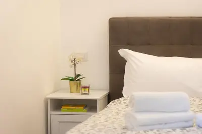 a bed with a brown headboard and a side table with towels at Vatican Apartment 2 minuti da città del vaticano in Rome