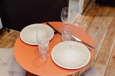 an orange table with two plates and glasses on it at Monti Urban Studio by Valentina's Dream in Rome