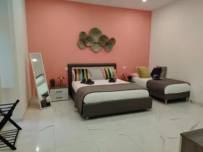 a bedroom with two beds and a pink wall at Emma and Livia's Vatican Suite 1 in Rome