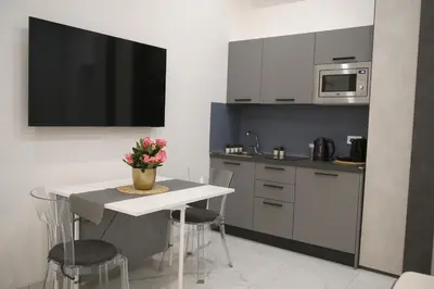a kitchen with a table and a tv on the wall at Emma and Livia's Vatican Suite 1 in Rome