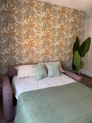 a bedroom with a bed and a wall with a flower pattern at Aulo Plauzio Apartment in Rome