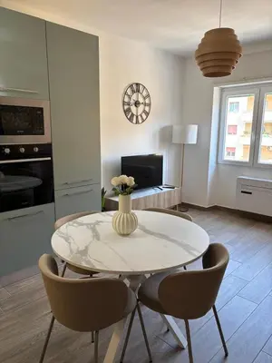 a dining room table with chairs and a vase with flowers at Aulo Plauzio Apartment in Rome