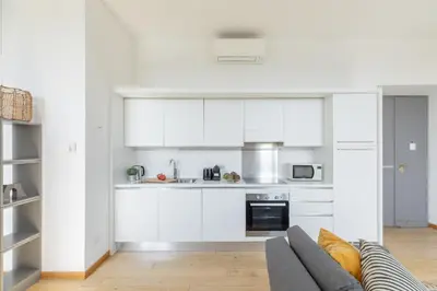 a kitchen with white cabinets and a gray couch at iFlat Bright & Modern Living with Panoramic View in Rome