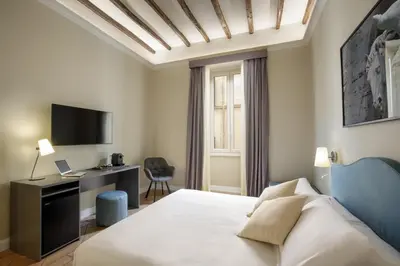 a bedroom with a bed and a desk and a tv at BeSecret Belsiana in Rome