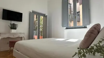 a white bedroom with a bed and a television at La bella vita Navona in Rome