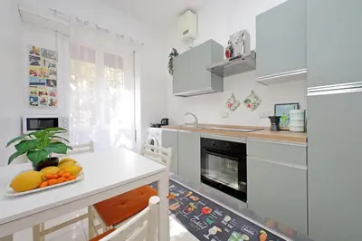 a kitchen with white cabinets and a table with a bowl of fruit at 4BNB - Annibaliano Metro Apartment in Rome