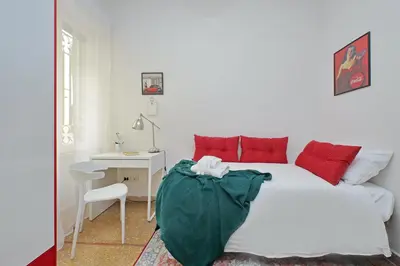 a bedroom with a white bed with red pillows and a desk at 4BNB - Annibaliano Metro Apartment in Rome