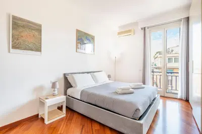 a white bedroom with a bed and a large window at Vatican Art Apartment in Rome