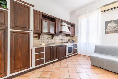 a kitchen with wooden cabinets and a couch at Vatican Art Apartment in Rome