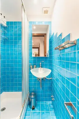 a blue tiled bathroom with a sink and a shower at Vatican Art Apartment in Rome