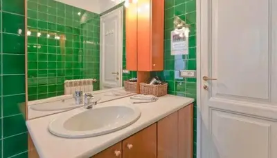a green tiled bathroom with a sink and a mirror at Saint Bon Apartment Good for Families in Rome