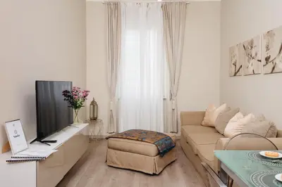 a white living room with a couch and a tv at Santamato Vatican Apartment in Rome