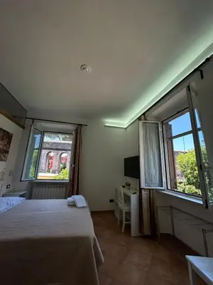 a bedroom with a bed and two windows at Villa Lanusei in Rome